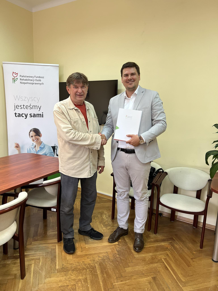 Pokaż zdjęcie: Dwóch uśmiechniętych mężczyzn podaje sobie dłoń