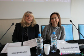 Pokaż zdjęcie: Przy stole podczas konferencji siedzą dwie kobiety, przed nimi stoją dwa mikrofony.