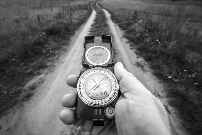 Pokaż zdjęcie: Fotografia czarno-biała przedstawiająca kompas i drogę