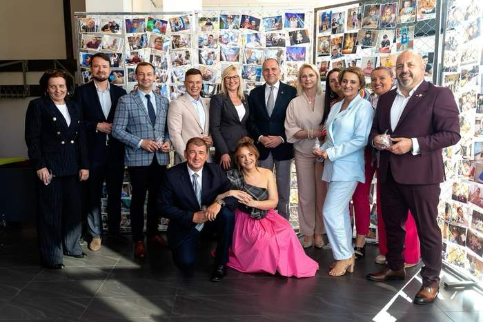 Pokaż zdjęcie: Grupa osób na scenie podczas Gali Tęczowych Serc w Drawsku Pomorskim. W tle kolorowa grafika z napisem „Do zobaczenia za rok”. Po lewej stronie dwoje dzieci wchodzi na scenę, z prawej strony ustawieni są wręczający nagrody, wśród nich Dyrektor Oddziału Zachodniopomorskiego PFRON.