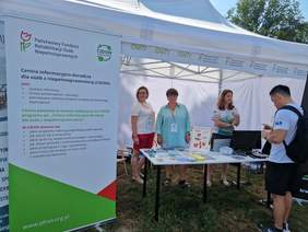 Pokaż zdjęcie: Stoisko PFRON w namiocie w Parku Jordana. Na stoisku pracownicy Oddziału udzielają informacji.