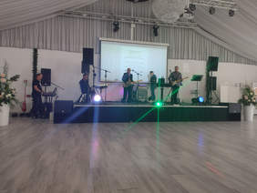 Na scenie zespół muzyczny 4 mężczyzn, piąty poza sceną z lewej strony sceny