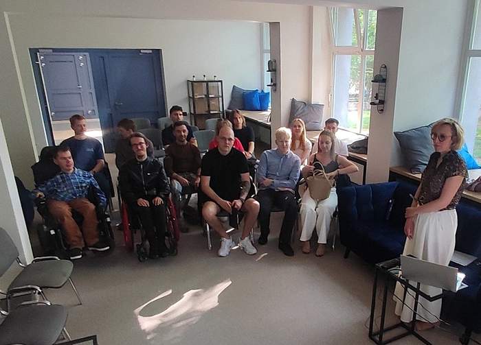 Pokaż zdjęcie: W niewielkiej sali w trzech rzędach siedzi grupa kilkunastu osób. Z przodu znajduje się kobieta, która prowadzi spotkanie i ma przed sobą laptop ustawiony na stoliku.