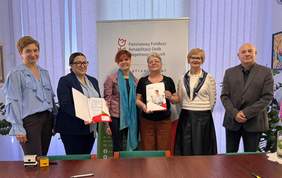 Pokaż zdjęcie: Sześć osób pozuje do pamiątkowej fotografii, w tle logo PFRON.