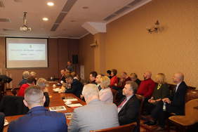 Pokaż zdjęcie: Sala konferencyjna w oddali ekran projektora, zgromadzeni uczestnicy spotkania.