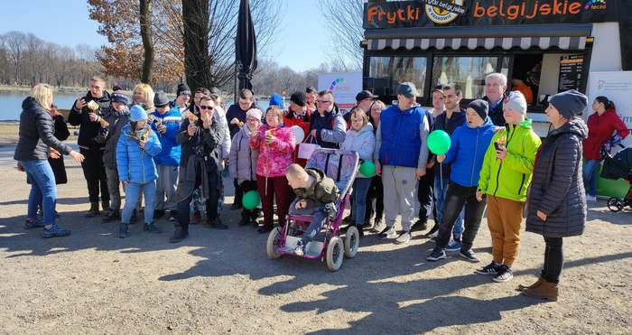 Pokaż zdjęcie: Liczna grupa pozuje na tle food truck`a Frytek Belgijskich 