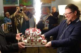 Pokaż zdjęcie: Osoby zgromadzone wokół urodzinowego tortu. 