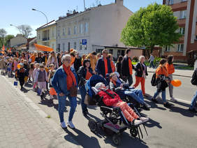 tłum z pomarańczowymi flagami maszeruje ulicami