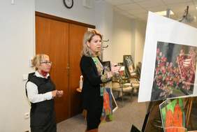 Plan zdjęcia stanowi sala w której na sztalugach ustawione są prace plastyczne. W centrum fotografii stoją członkowie komisji konkursowej.