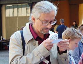 Pokaż zdjęcie: 4.	Uczestnik spotkania sprawdza, jak się czyta patrząc przez lupę