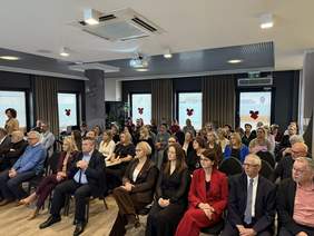 Pokaż zdjęcie: Zdjęcie osób siedzących w pierwszych rzędach podczas konferencji.