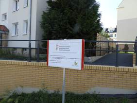 Pokaż zdjęcie: Wielorodzinne budynki mieszkalne wraz z nowo wybudowanymi chodnikami, pochylniami oraz balustradami. Pomiędzy budynkami widoczne są krzewy iglaste oraz liściaste różnej wielkości, jak również ogrodzenia oddzielające poszczególne zabudowania. Przed balustradą zamontowana została tabliczka z logo PFRON i Spółdzielni Mieszkaniowej Zielone Wzgórza w Murowanej Goślinie. Tabliczka informuje o tym, że projekt pn. „Likwidacja barier architektonicznych przy wielorodzinnych budynkach mieszkalnych oraz najbliższej okolicy na terenie Osiedla Zielone Wzgórza w Murowanej Goślinie”, o całkowitej wartości 968 478,52 zł, został dofinansowany ze środków PFRON w ramach obszaru A „Programu Wyrównywania Różnic Między Regionami III”.