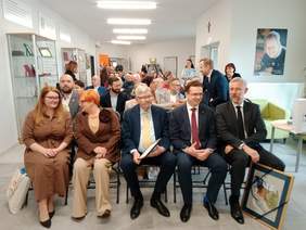 Pokaż zdjęcie: W domu mieszkalnym w Zgierzu siedzi w rzędach kilkadziesiąt osób. Są przedstawiciele władz, instytucji oraz osoby z niepełnosprawnościami. Niektórzy trzymają w dłoniach prezenty i upominki. 