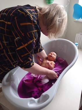 Pokaż zdjęcie: Kobieta kąpie niemowlaka w wanience