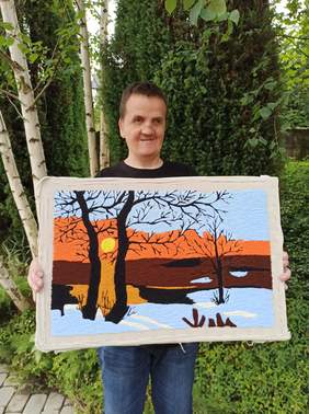 Pokaż zdjęcie: Uczestnik WTZ prezentuje wykonaną przez siebie pracę plastyczną