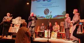 Pokaż zdjęcie: Wręczenie medali św. Brata Alberta. Na scenie laureaci, organizatorzy oraz prowadzący uroczystość. W tle ekran z napisem "Albertiana"