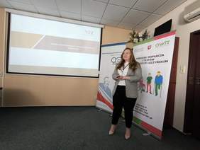 Pokaż zdjęcie: Wykład prowadzi kobieta z długimi włosami w okularach.