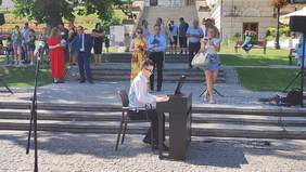 Na przemyskim rynku chłopiec gra na pianinie, za nim przechodnie