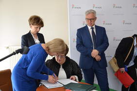 Pokaż zdjęcie: Dwie osoby podpisują umowę
