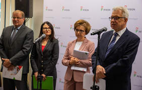 Pokaż zdjęcie: Briefing, osoby stojące na tle ścianki z logoi PFRON