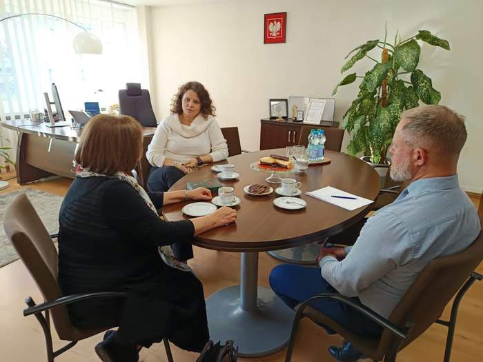 Dwie kobiety i mężczyzna, siedzą przy stole, rozmawiają