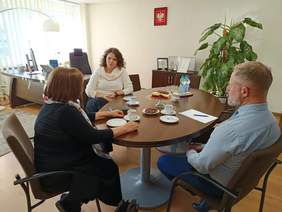 Dwie kobiety i mężczyzna, siedzą przy stole, rozmawiają