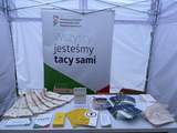 Pod namiotem na stole znajdują się materiały promocyjne, w tle roll-up PFRON