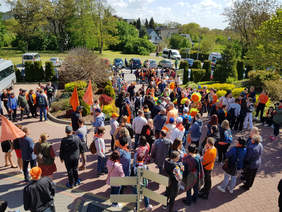 widok z góry na tłum zebranych ludzi, pomarańczowe elementy ubrań, balony, słoneczny dzień