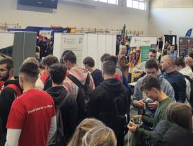 Tłum osób, w tle widać logotypy różnych instytucji, w tym logo PFRON.