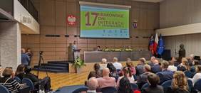 Pokaż zdjęcie: Aula wypełniona ludźmi. Na ekranie wyświetlone logo Krakowskich Dni Integracji.