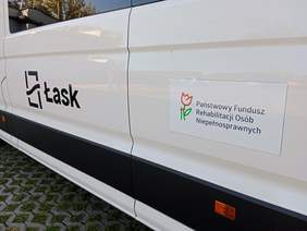 Pokaż zdjęcie: Na samochodzie nalepiona jest naklejka z logo PFRON. Obok niej jest napis: Łask. 