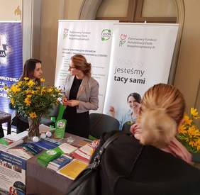 Pokaż zdjęcie: Uczestnicy Dnia Osób z Niepełnosprawnością w Ostrowie Wielkopolskim przy stoisku Oddziału Wielkopolskiego PFRON