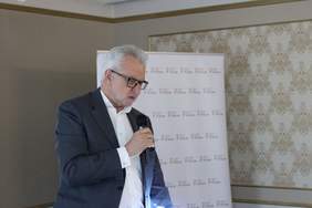 Pokaż zdjęcie: mężczyzna z mikrofonem w tle baner z napisem 30 lat PFRON