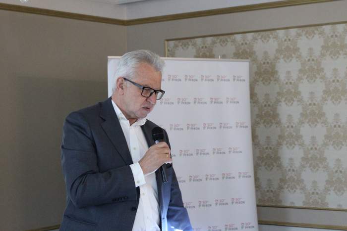 Pokaż zdjęcie: mężczyzna z mikrofonem w tle baner z napisem 30 lat PFRON