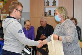 Pokaż zdjęcie: Kobieta przekazuje młodemu mężczyźnie gratulacje poprzez uścisk dłoni