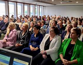 Pokaż zdjęcie: Zdjęcie uczestników konferencji siedzących na krzesełkach.
