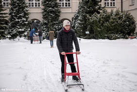 Pokaż zdjęcie: dr hab. Bogusław Marek jadący na sankach na tle budynków Katolickiego Uniwersytetu Lubelskiego fot. KUL