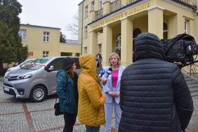 Pokaż zdjęcie: Przed budynkiem starostwa powiatowego w Lublinie stoją dwa nowe busy, na pierwszym tle kobieta ubrana w liliowy garnitur udziela wywiadu dla telewizji TVP3 Lublin