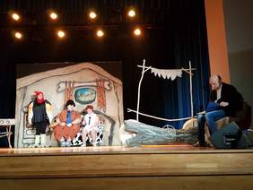 Przedstawienie na scenie. 4 aktorów, sceneria prehistoryczna