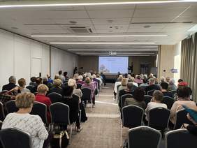 Pokaż zdjęcie: Zdjęcie z tyłu sali w kierunku prelegenta. Na ścianie slajd z prezentacją na temat dziedziczenia ustawowego.