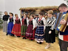 Pokaż zdjęcie: Na scenie grupa śpiewaków przebrana w stroje ludowe. 