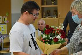 Pokaż zdjęcie: Młody mężczyzna wręcza bukiet kwiatów kobiecie