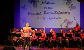 Na scenie gra orkiestra w czerwono-czarnych strojach