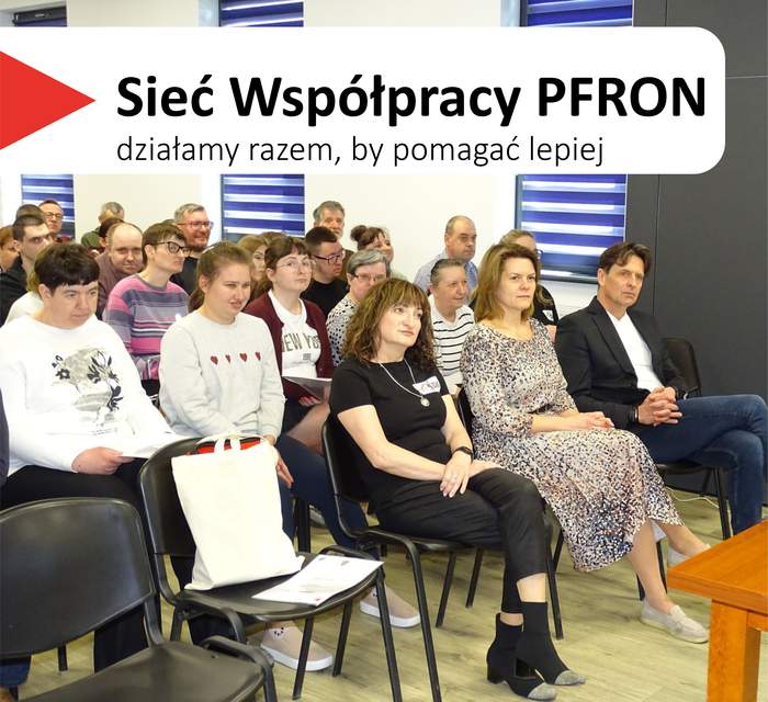 Pokaż zdjęcie: Spotkanie informacyjne w Środowiskowym Domu Samopomocy w Gostyniu. Wypełniona sala: w pierwszym rzędzie siedzą trzy kobiety i mężczyzna, za nimi kilkanaście kolejnych osób zwróconych ku prowadzącemu. W lewym górnym rogu widnieje hasło „Sieć Współpracy PFRON – działamy razem, by pomagać lepiej”.