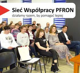 Spotkanie informacyjne w Środowiskowym Domu Samopomocy w Gostyniu. Wypełniona sala: w pierwszym rzędzie siedzą trzy kobiety i mężczyzna, za nimi kilkanaście kolejnych osób zwróconych ku prowadzącemu. W lewym górnym rogu widnieje hasło „Sieć Współpracy PFRON – działamy razem, by pomagać lepiej”.
