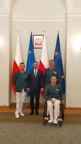 Pokaż zdjęcie: 2 zawodników (w tym jeden na wózku inwalidzkim) i 1 trener "Start" Gorzów stoją obok Prezydenta Polski Adrzeja Dudy na tle flag Polski i Unii Europejskiej w sali Pałacu Prezydenckiego