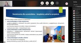 Pokaż zdjęcie: na zdjęciu kadr ze spotkania on-line w tle osoba przedstawiająca prezentację na której znajdują się dane o projekcie, w prawym dolnym rogu prezentacji znajduje się kolorowa kanapa i fotele, stół wskazujące na pomieszczenie do rehabilitacji 