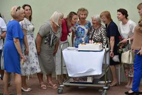 Pokaż zdjęcie: Na stoliku tort, wokół niego zebrały się kobiety i zdmuchują świeczkę z cyfrą 40.