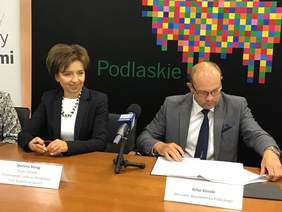 Pokaż zdjęcie: Osoby podpisujące porozumienie, w tle napis Podlasie, logo kolorowy żubr