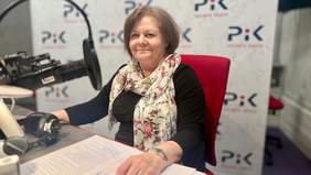 Kobieta w czarnej sukience, szalu w kwiaty, w tle napis Radio PiK